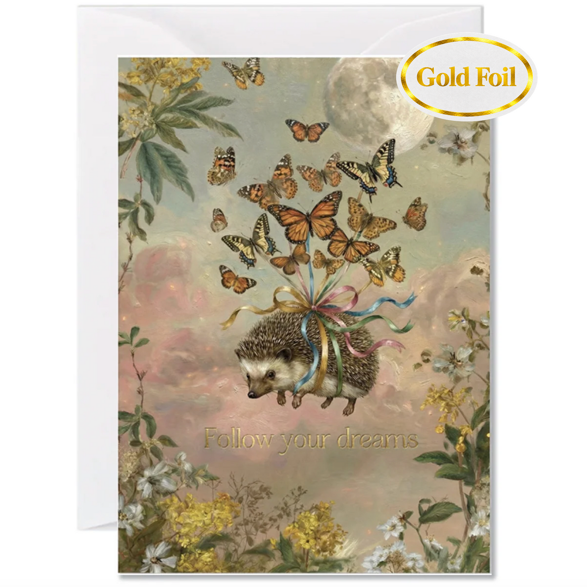 A greeting card featuring an illustration of a small hedgehog flying upward with a bundle of colorful ribbons, surrounded by butterflies, flowers, and a full moon. 'Follow your dreams' is the message written in gold foil under the flying hedgehog.The card includes a white envelope behind it and a gold foil seal in the top right that reads 'Gold Foil'.