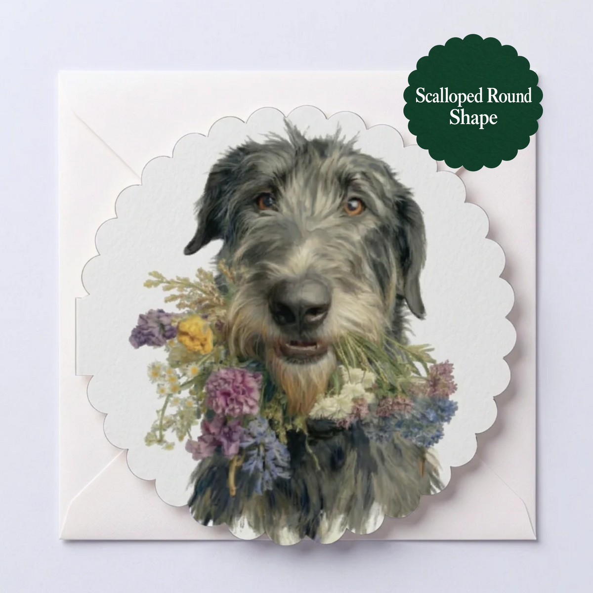 A square envelope with a scalloped round greeting card featuring a watercolor portrait of a gray wolfhound dog surrounded by small purple, yellow, and white flowers. The card is shown on a white envelope , with a dark green badge in the top right reading 'Scalloped Round Shape'.