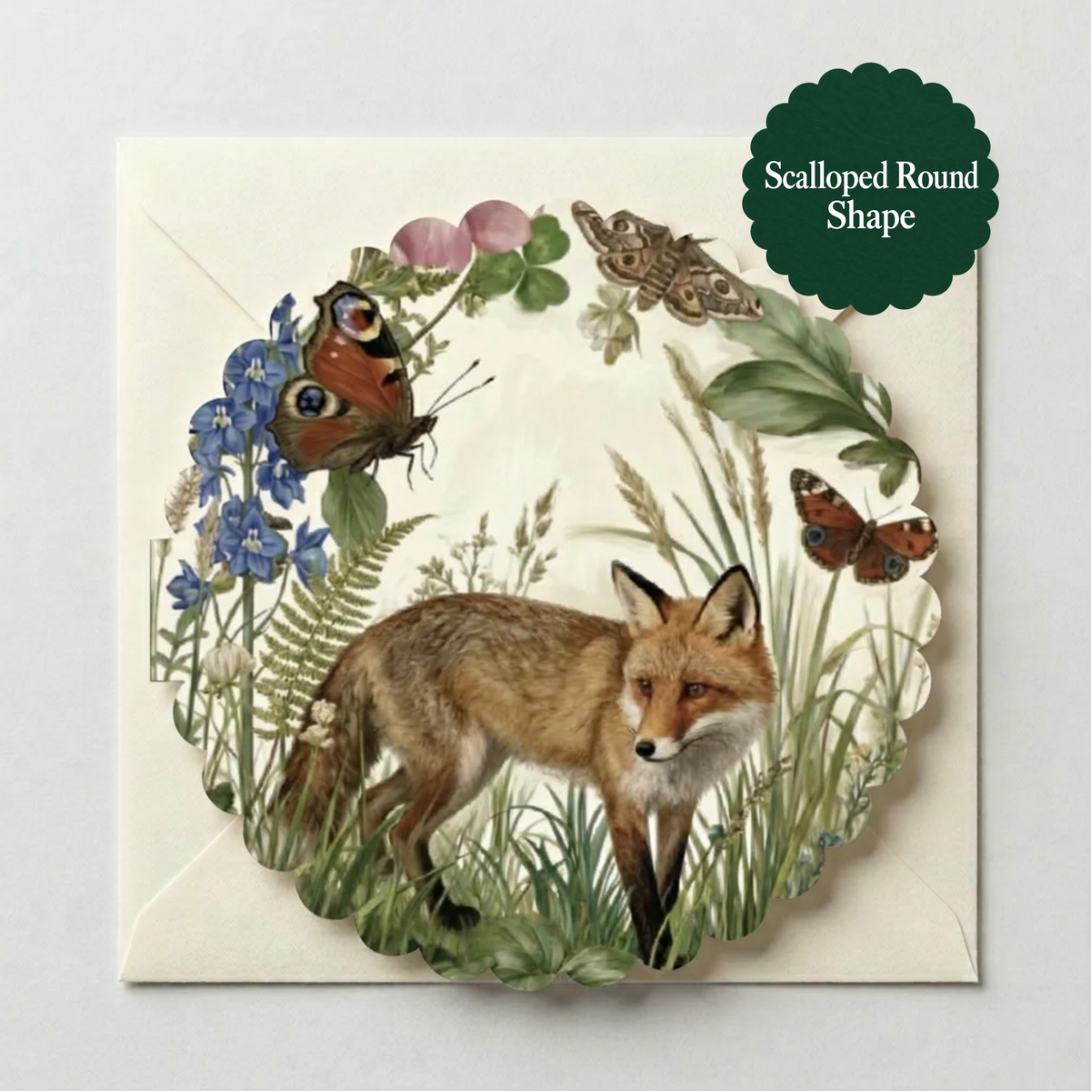 A square scalloped greeting card featuring an illustrated fox surrounded by grass, flowers, and butterflies, shown on a light neutral background with a green badge that reads 'Scalloped Round Shape'.