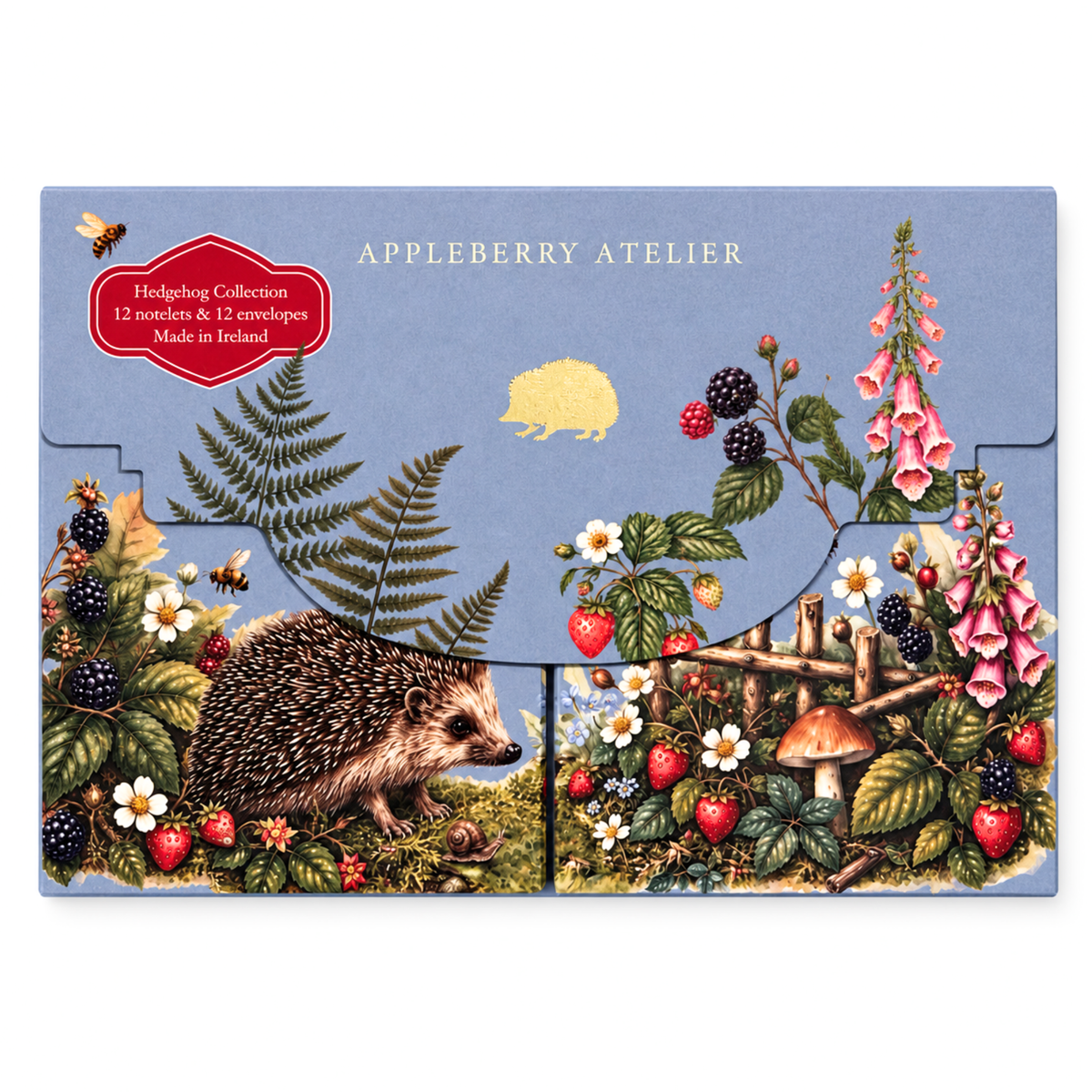 A flat-lay product shot of an Appleberry Atelier Hedgehog notelet set, featuring 12 nested envelopes decorated with vintage-style forest illustrations including a hedgehog, strawberries, foxglove, ferns, and a mushroom on a dusty blue background.