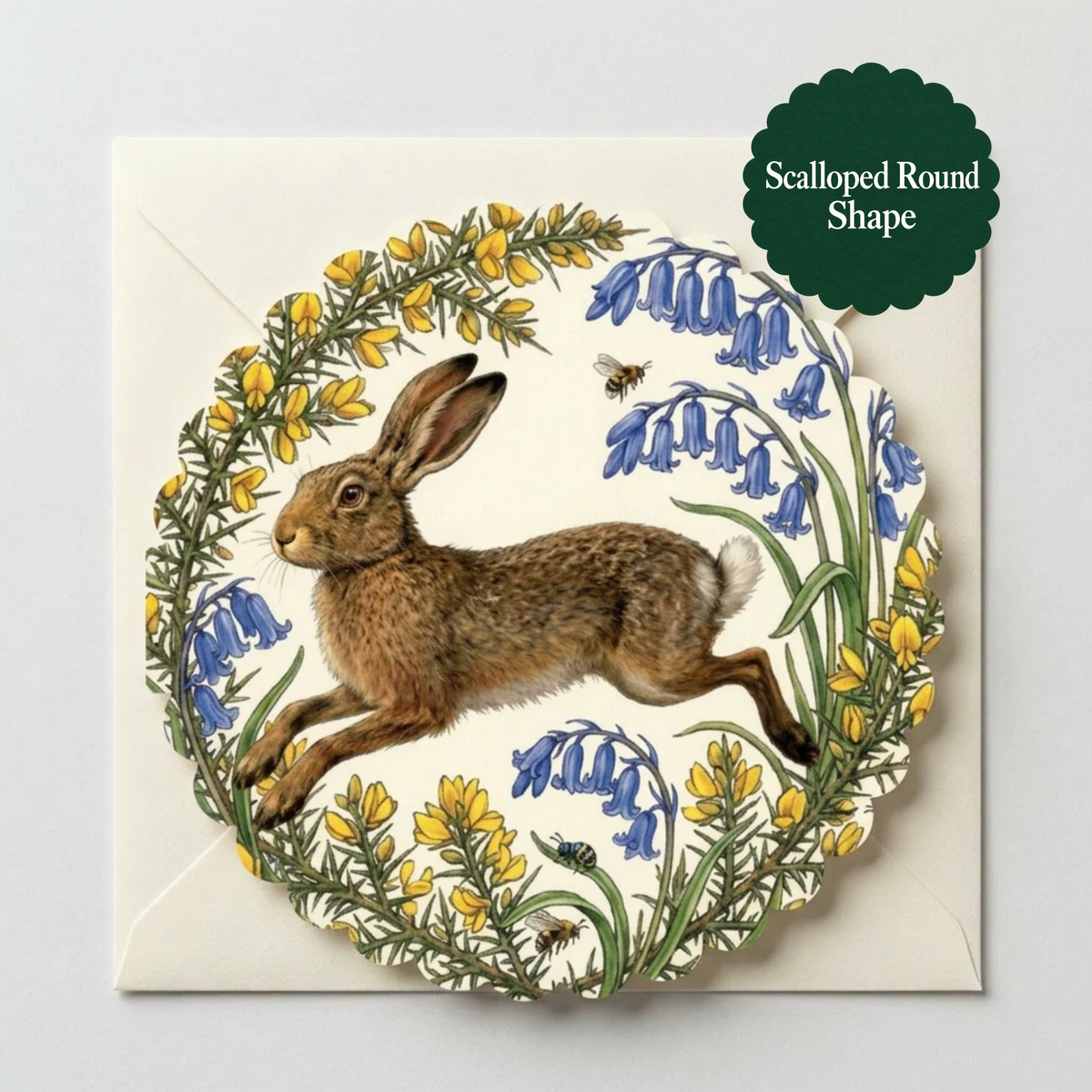 A scalloped round card featuring an illustration of a brown hare surrounded by blue bellflowers and yellow gorse, shown on a light gray background with a dark green label that reads 'Scalloped Round Shape'.
