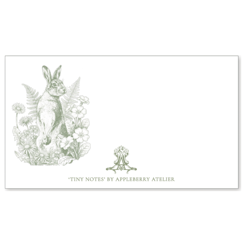 A white rectangular card or notepad with a pale green illustrated rabbit among flowers on the left, a small matching crest near the bottom center, and the text 'TINY NOTES BY APPLEBERRY ATELIER' at the bottom.